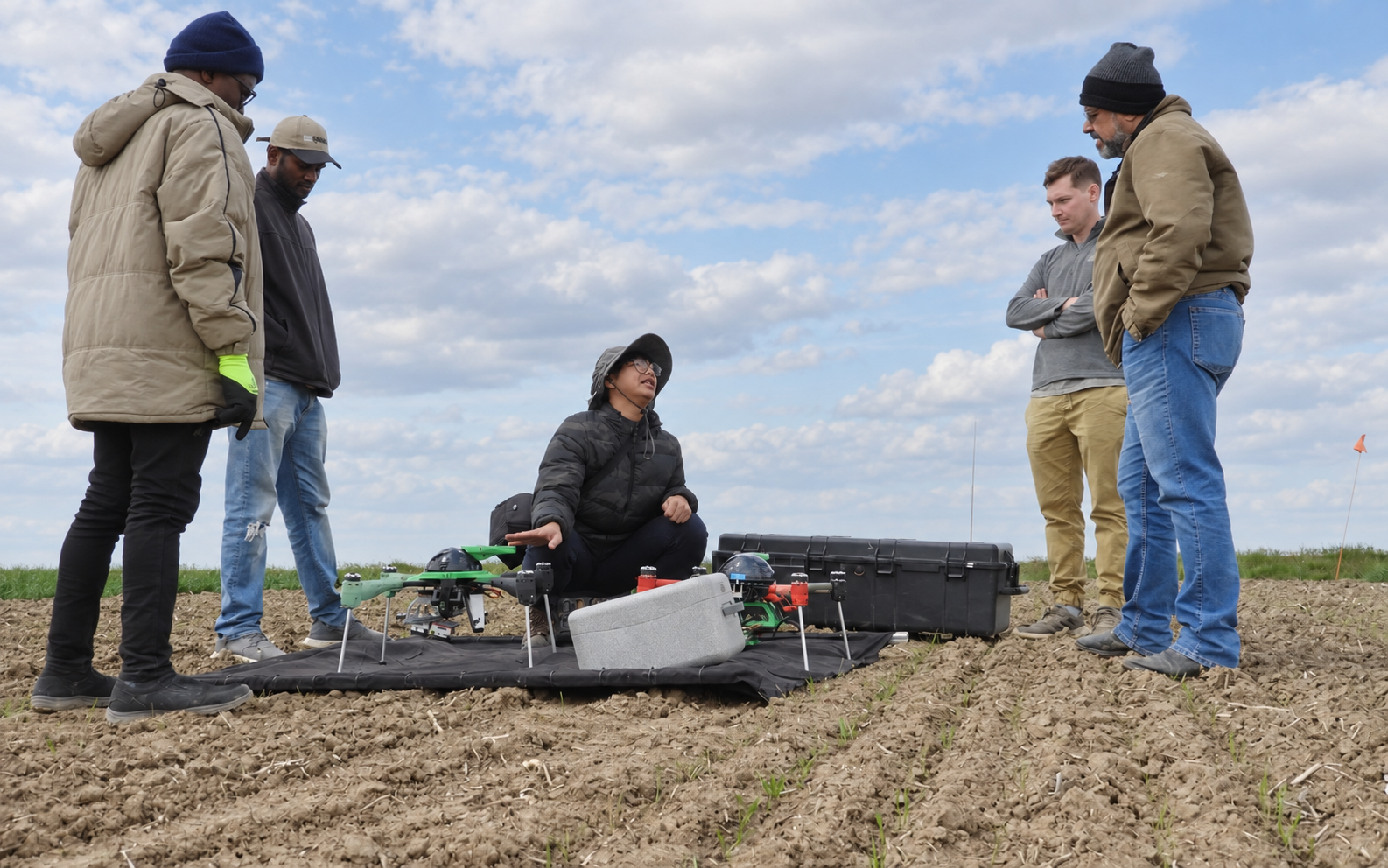 Worasit demonstrating UAV equipment to a group in the field